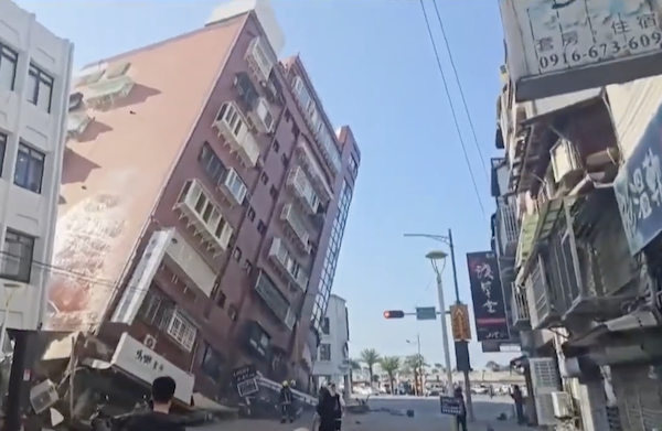 A Taiwanese multi-story building rests at at awkward angle as the lower floors on one corner of the building have collapsed.