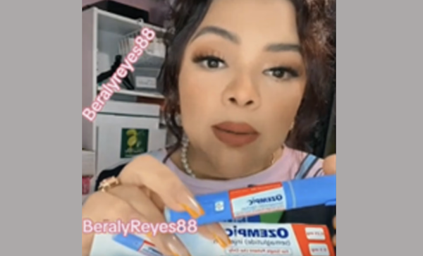 Screenshot of a TikTok creator with glamorous makeup and styled medium brown hair holding up what looks like an Ozempic box to the camera.