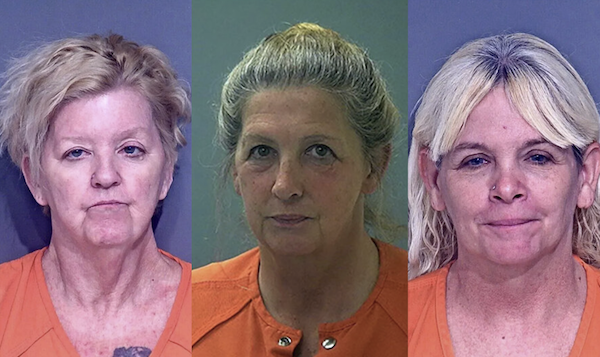 Three side-by-side mugshots of blonde women of similar late-middle age all wearing orange shirts. On the left a woman with short hair frowns slightly. In the middle, a woman with medium blonde long hair worn pulled back in a bun is expressionless. On the right a woman with long very light blonde hair and bangs smiles slightly.