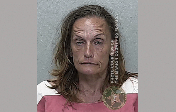 Mugshot of a woman with shoulder-length light brown hair wearing a pink and white jail uniform against a gray wall, with Marion County Sheriff’s Office Florida photo markings.