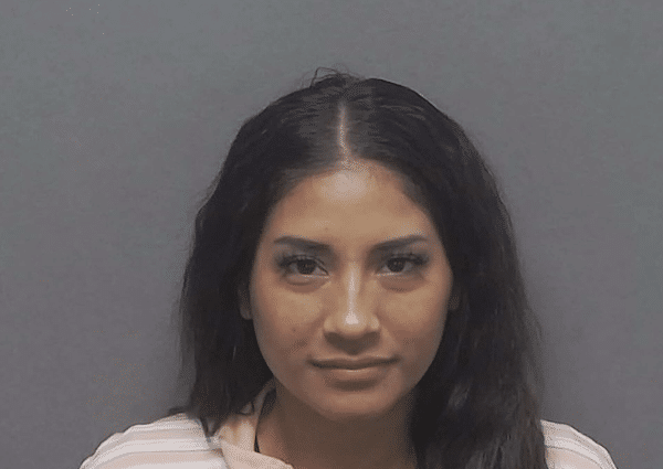 Portrait of a woman with long dark hair, facing the camera against a gray background with a neutral expression.