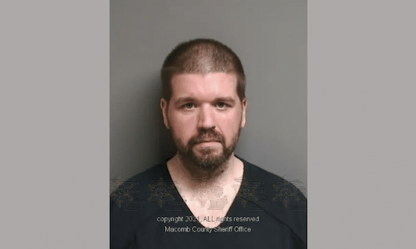 Man with short hair and a beard faces the camera against a gray background.